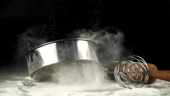 Super Slow Motion Sieve Falls on the Table with Flour and Whisk