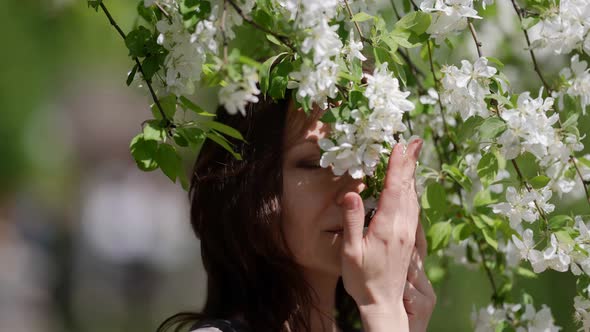 Portrait of a Brunette Through the Branches of a Blooming Apple Tree