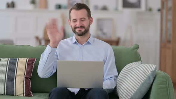 Online Video Call on Laptop By Young Man on Sofa