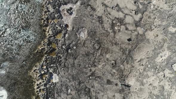 Topdown ascending view revealing volcanic rocks shore, waves crashing, Ko Olina, Hawaii