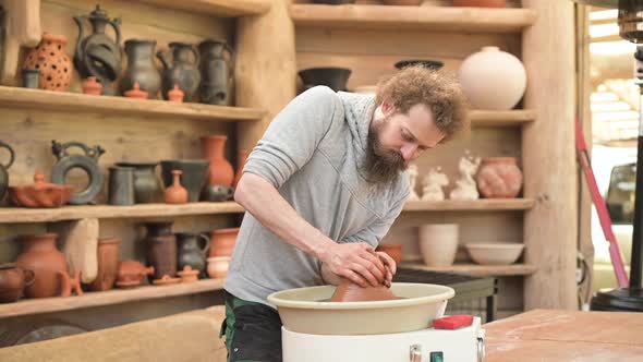 pottery master sticks a piece of clay to a potter's wheel and begins creating