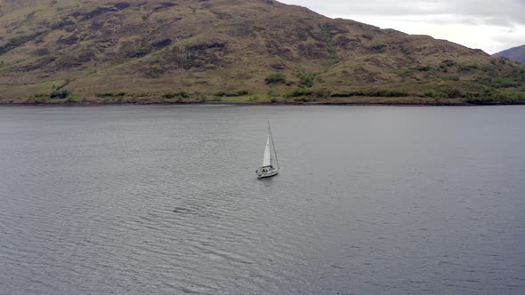 A Yacht Raising Sail Surrounded By Mountains and Forests in a Lake