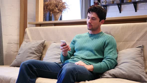 Man Browsing Online on Smartphone Typing Message Relaxing at Home