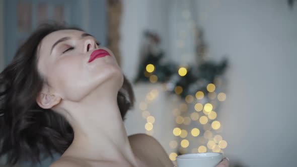 Portrait of Passionate Lady Drinks Tea and Smiles at Camera