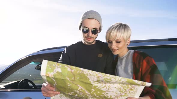 Couple of Traveler in Love Standing in front of Car and Considering the New Routes a Map