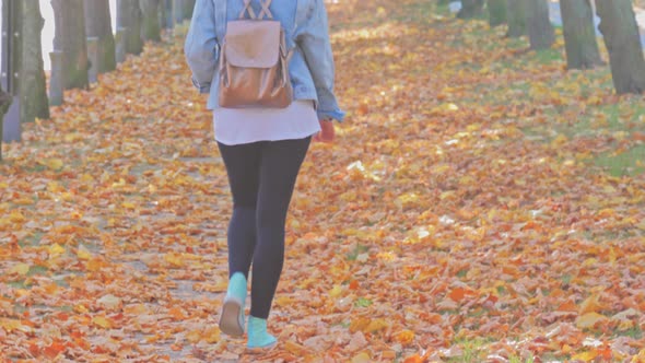 Woman with Backpack Walking in Park