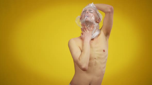 Portrait of Young Caucasian Man with Plastic on Head Posing at Yellow Background