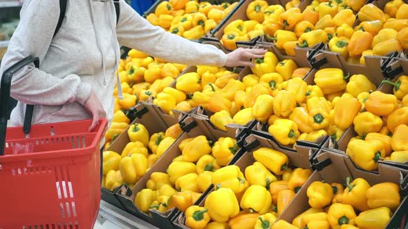 A Woman's Hand Takes Yellow Vegetables in a Supermarket