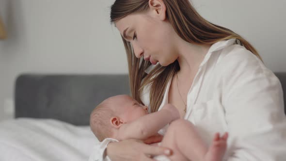 Mother Caressing Crying Newborn Son on Hands