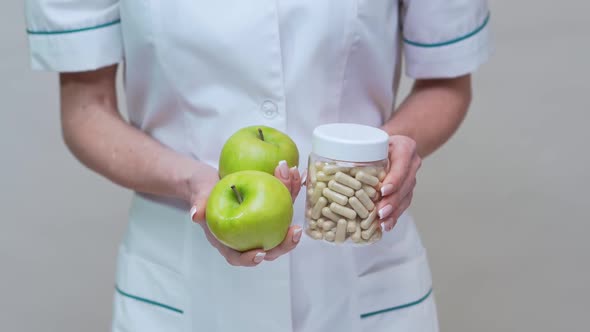 Nutritionist Doctor Healthy Lifestyle Concept - Holding Organic Green Apple and Jar of Vitamin Pills