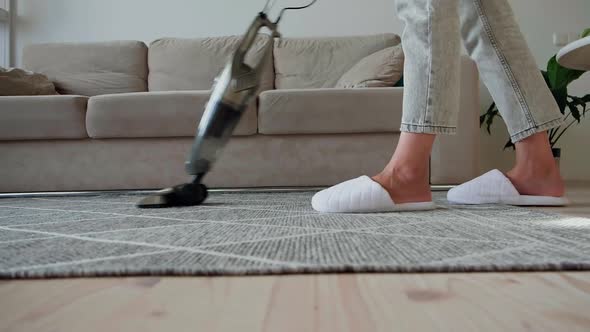 Young Woman Legs in Sneakers Cleaning Carpet with Vertical Vacuum Cleaner While Cleaning the House