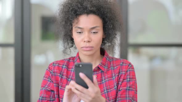 African Woman Reacting to Loss on Smartphone