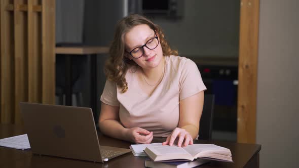 Woman is Sitting at Her Desk and Reading Book