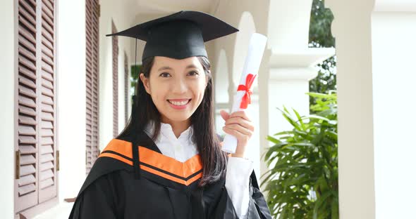 Asian woman wearing graduation gown