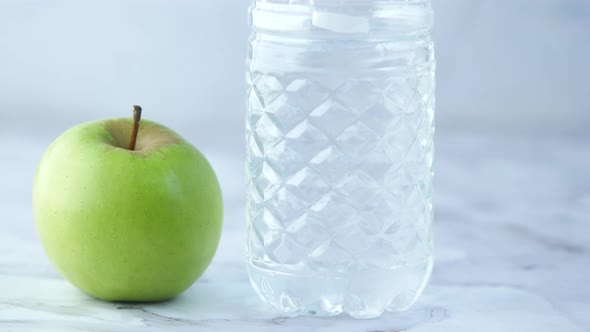 Fresh Drinking Water Apple and a Pink Color Dumbbell on Table