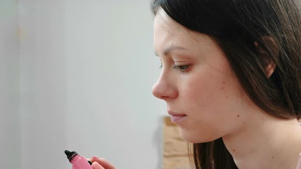 Woman Removes the Excess Mascara From the Brush To Paint the Eyes.