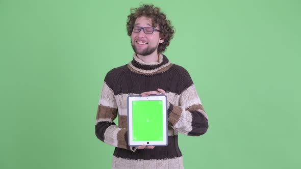 Happy Young Bearded Man Thinking While Showing Digital Tablet