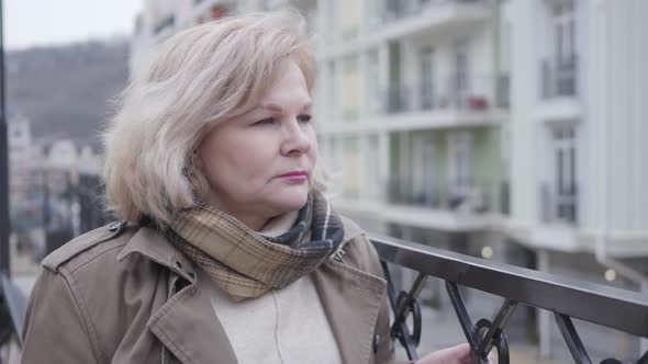 Close-up Portrait of Sad Senior Caucasian Woman Outdoors. Lonely Female Retiree in Autumn Scarf