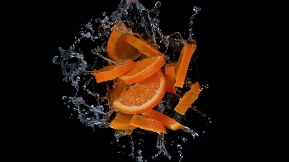 Super Slow Motion Shot of Rotating Exploded Orange Slices with Splashing Water on Black at 1000Fps