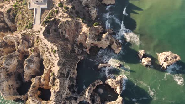 Cinematic aerial bird eye view of rocky formations located in Praia dos Estudantes Algarve