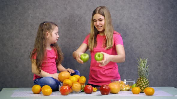 Mother and daughter playing with fresh fruit