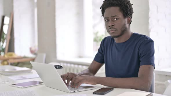 African Man Saying No with Finger Sign While Working on Laptop