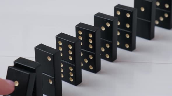 Dominoes Falling in a Row Hand Pushes a Domino and Starts a Chain Reaction Slow Motion