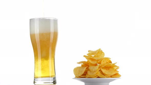 Beer and chips. Pouring beer in glass on white background. 4K UHD video