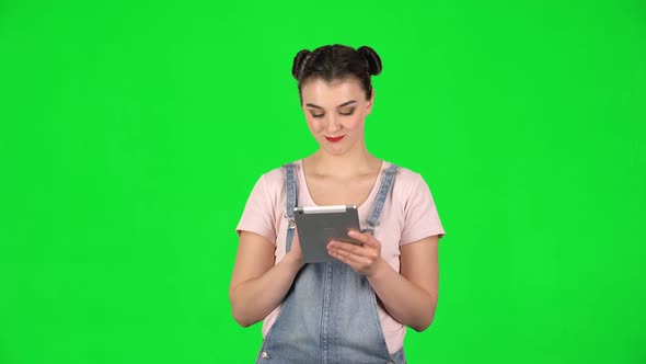 Young Smiling Woman Texting on Her Tablet Computer on Green Screen