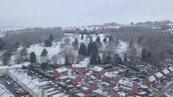 Forward tracking drone shot of snowy Exeter over a wooded area CROP