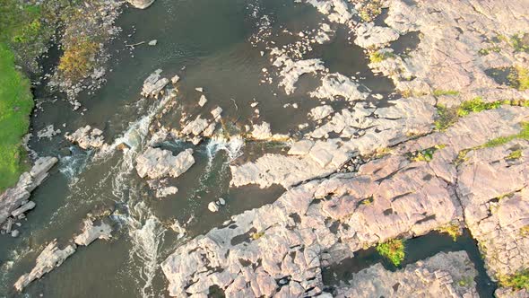 Flyover of Falls Park in South Dakota. Water gently flowing around the stones and splashing over.