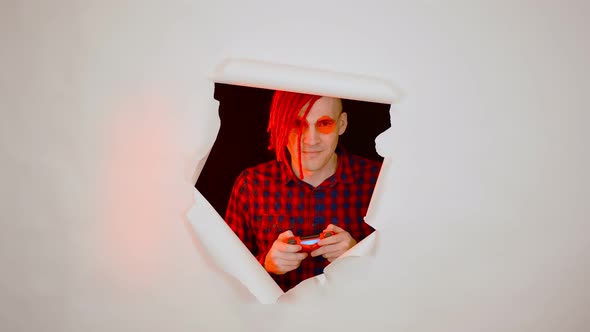 Young Man in Red Plaid Shirt with Gamepad and Playing Video Game