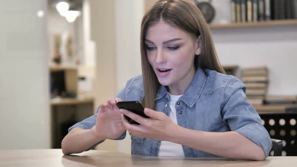 Young Woman Excited for Success While Using Smartphone