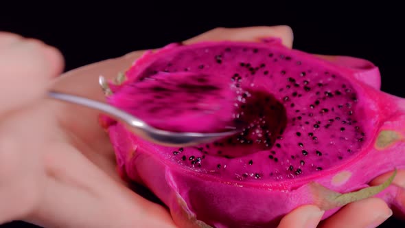 Eating Dragon Fruit or Pitaya with a Spoon in Female Hands