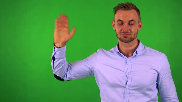 Young Handsome Business Man Waves with Hand - Green Screen - Studio