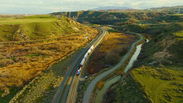 AERIAL - Train on railroad tracks among mesas, Bluffdale, Utah, circle pan