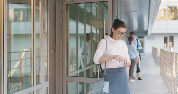 Young Businesswoman Leaving Office Building and Disinfecting Hands with Sanitizer