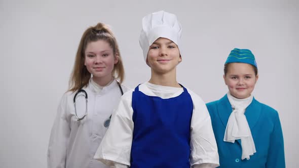 Portrait of Confident Boy in Chef Cook Uniform Posing Crossing Hands Looking at Camera with Girls in