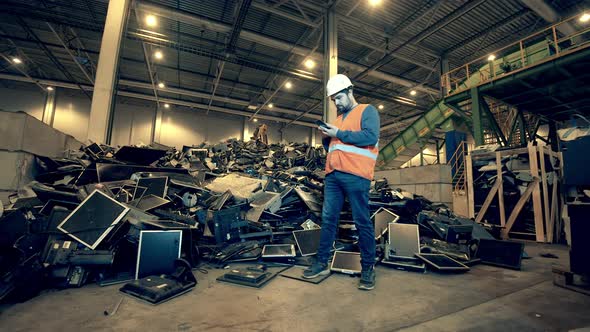 Male Worker Is Examining a Pile of Broken Computers