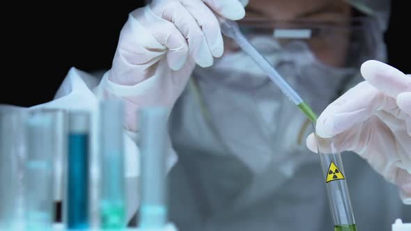 Person in Protective Uniform Adding Radioactive Liquid in Test Substance, Lab