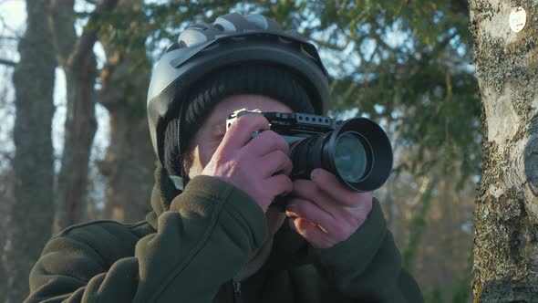 Man taking photos within forest at golden hour. Portrait shot 4K