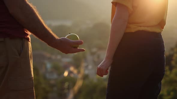 Man offers the woman an apple, and she take it. Close up.