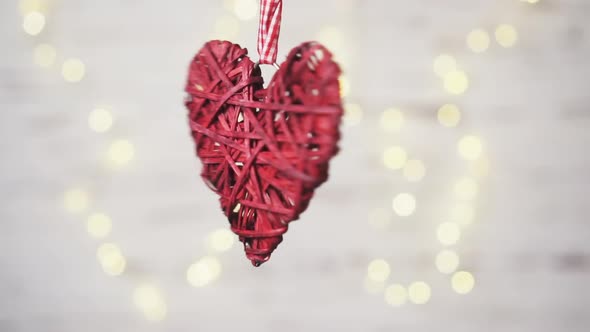 Red Wicker Heart Rotates on a White Background with Warm Bokeh.