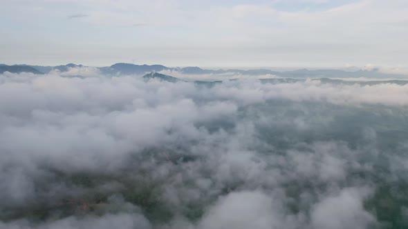 Aerial view of sunrise above fluffy sea fog misty clouds with mountain hill