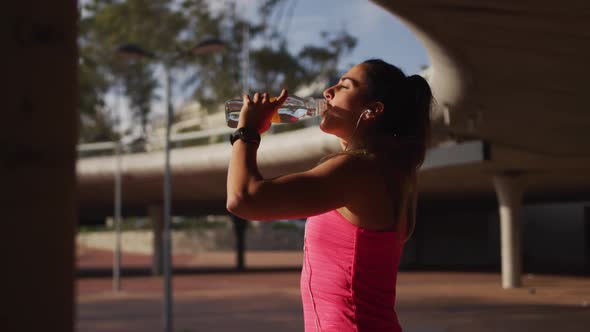 Caucasian woman drinking water under a bridge