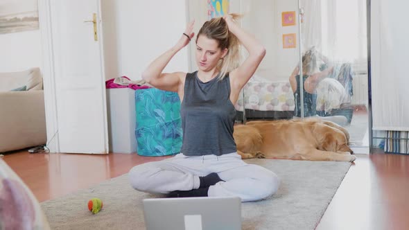 Woman in sports clothing sitting on floor in front of laptop, Milan, Italy