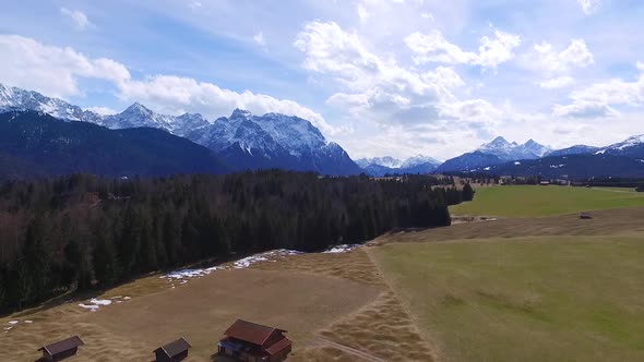 Aerial of green fields forest and mountains in the background