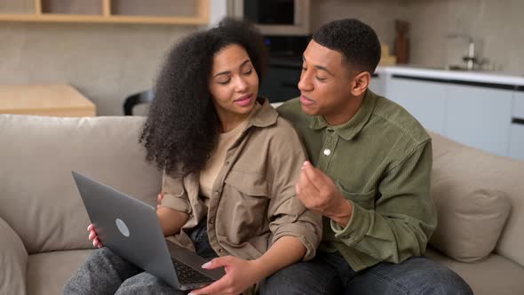 Young Multiracial Couple Using Laptop While Sitting at the Sofa at Home