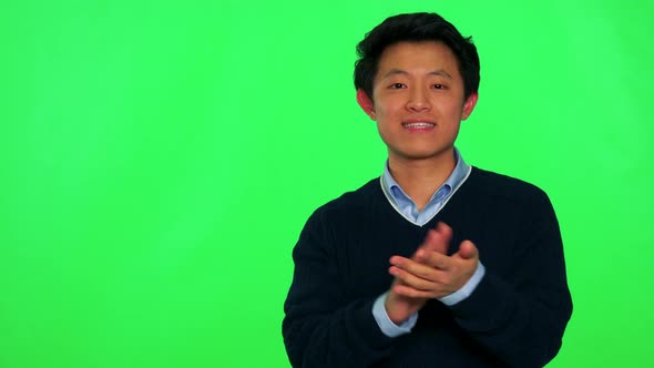 A Young Asian Man Smiles at the Camera and Claps His Hands - Green Screen Studio