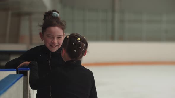 Two Little Smiling Girls Figure Skaters Meeting in the Gates of Public Rink and Talking